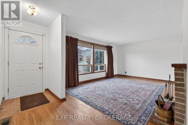 Living room featuring hardwood flooring, large window, and decorative area rug. - 19 Convay Crescent, Brockville