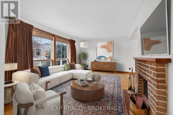 Stylish living room with modern furniture, large window, and brick fireplace. - 19 Convay Crescent, Brockville