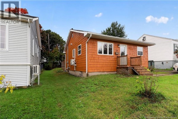 Angle of orange wood-shingled bungalow with green lawn and adjacent properties. - 19 Copp Street, Dieppe