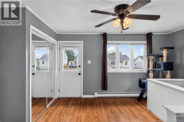 Living room with grey walls, hardwood floors, mirrored closet, and cat tree. - 19 Copp Street, Dieppe