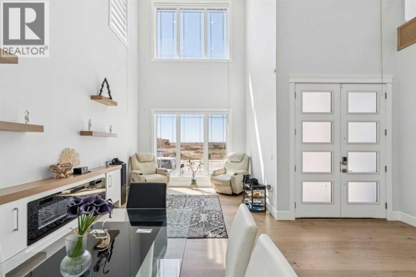Open-concept living area with a high ceiling, large windows, and light wood flooring. - 19 Duhram Way, Rural Rocky View County
