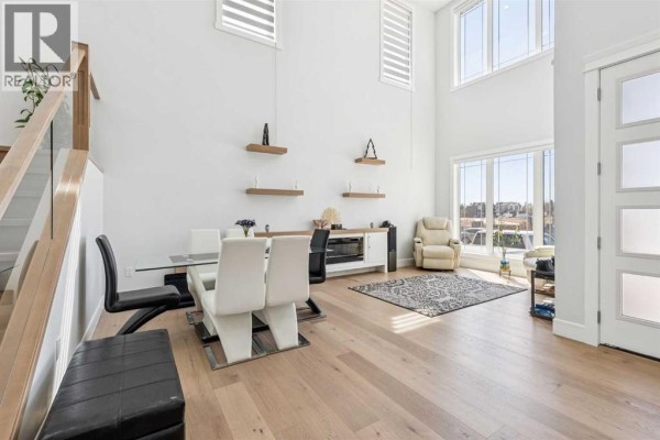 Dining area with a glass table and white chairs adjacent to a living area with recliners. - 19 Duhram Way, Rural Rocky View County