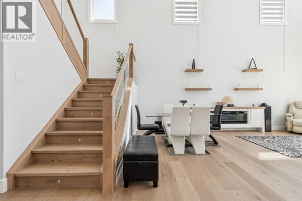 Wooden staircase with glass railings leading to the upper level of the house. - 19 Duhram Way, Rural Rocky View County