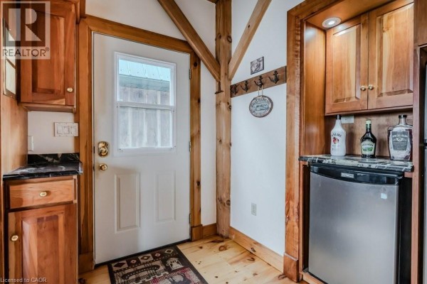 Interior entryway with wooden beams, white door, wood cabinets, granite countertop, and a mini-fridge. - 19 Eagle Road, Tobermory