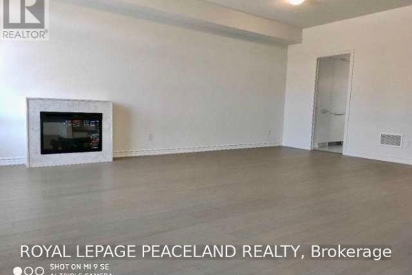 Living room with light wood floors, a modern white fireplace surround, and a doorway. - 19 Frank Charlton Avenue, Markham