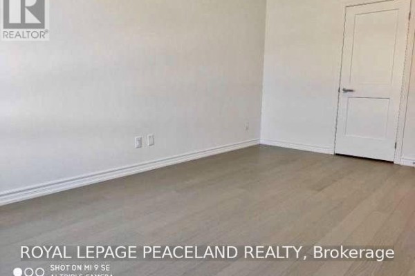 Empty room with light wood floors and a closed white door on the right wall. - 19 Frank Charlton Avenue, Markham
