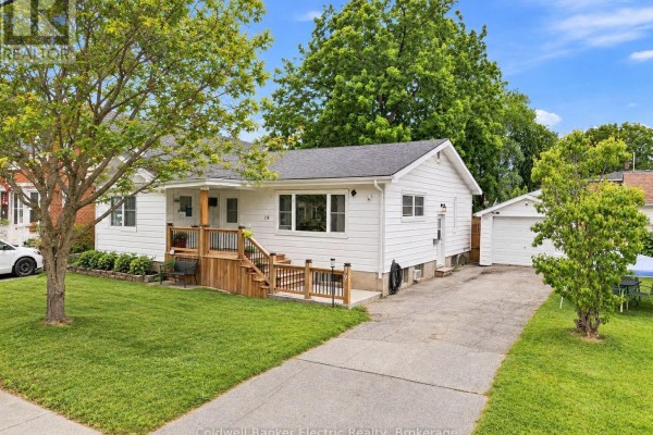 Front view of a white bungalow with a long driveway leading to a detached garage. - 19 Graham Street E, Greater Napanee