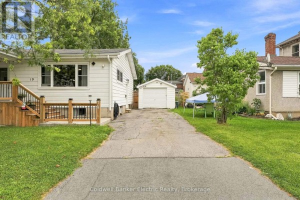 Side exterior view of the bungalow showing the driveway, garage, and backyard. - 19 Graham Street E, Greater Napanee