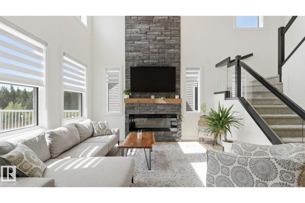 Rear exterior of a grey two-story house with a large wooden deck and stairs. - 19 Holt Cv, Spruce Grove