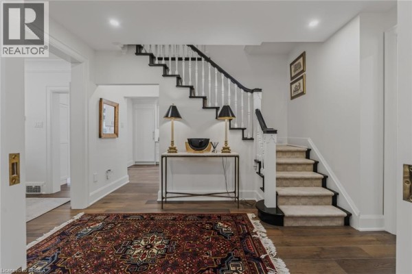 Foyer with a staircase, dark wood floors, and a patterned rug leading to the stairs. - 19 Inwood Drive, Brantford