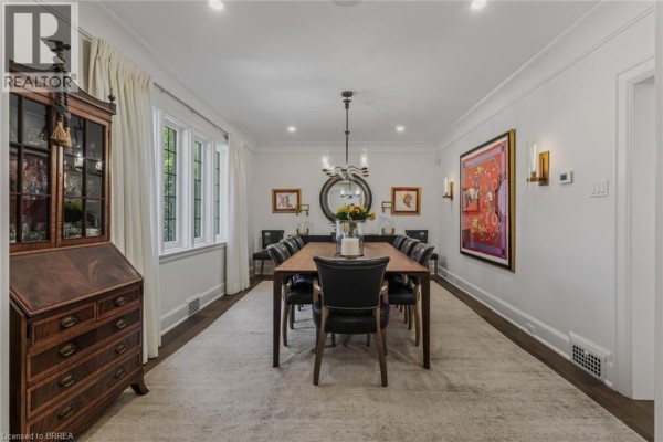 Formal dining room with a dark wood table, chairs, a china cabinet, and artwork on walls. - 19 Inwood Drive, Brantford
