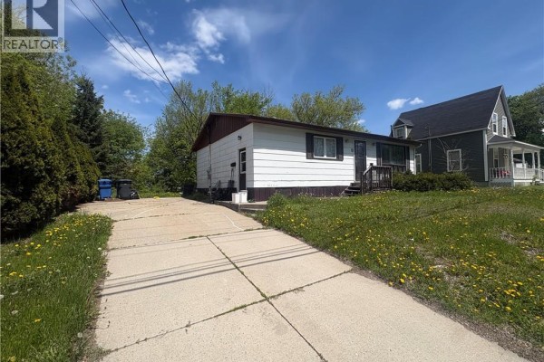 Side view of the house with a concrete driveway and neighboring properties. - 19 John Street, Miramichi
