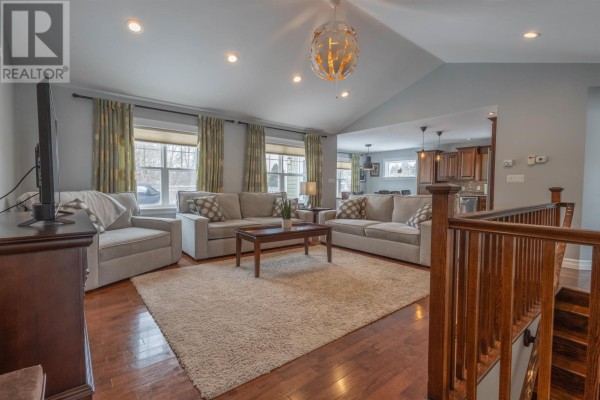 View of a kitchen island with three bar stools, stainless steel appliances, and wood floors. - 19 Kehough Court, Cornwall