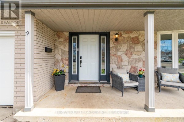 Front door and porch area with stone accent wall, white columns, and seating. - 19 Kendall Court, London North