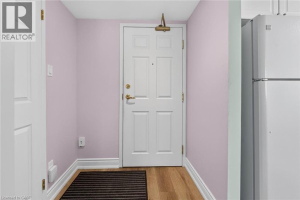 Interior entryway with light purple walls, hardwood floor, and white refrigerator. - 19 Lake Avenue S Unit# 303, Stoney Creek