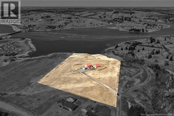 Overhead drone shot of a rural property with a house and outbuildings surrounded by fields, with a river and distant town in the background. - 19 Leopold Goguen Road, Sainte Marie De Kent