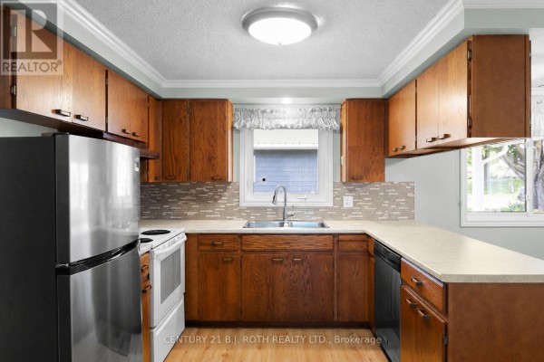 Kitchen with oak cabinets, stainless steel refrigerator, sink, and dishwasher. - 19 Maple Crescent, Oro Medonte