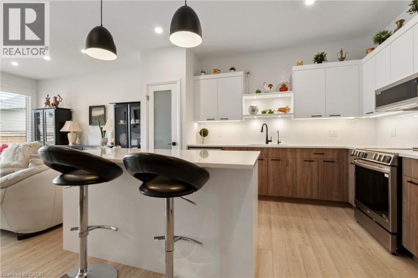 Kitchen island with two black bar stools and view into living area. - 19 Martin Street, Tillsonburg