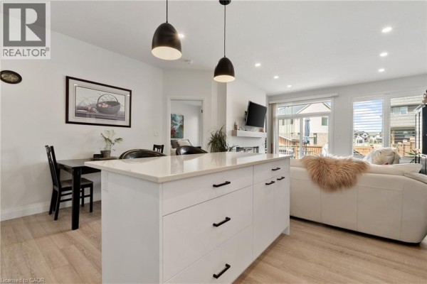 Open-concept living and dining area with kitchen island, fireplace, and large windows. - 19 Martin Street, Tillsonburg