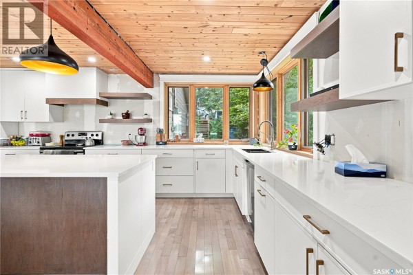 Modern white kitchen with wood accents, island, and window overlooking greenery. - 19 Mawson Drive, Shields