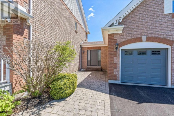 Close-up of a paved walkway leading to the front entrance between a brick house and an attached garage. - 19 Mccullogh Drive, Erin