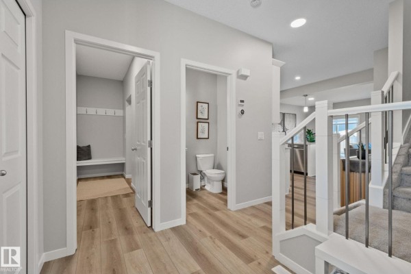 Hallway showing doors to a mudroom and bathroom, with stairs and kitchen in background. - 19 Meadowbrook Wy, Spruce Grove