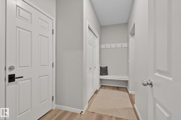 Mudroom area with a built-in bench, coat hooks, and a rug on wood-look flooring. - 19 Meadowbrook Wy, Spruce Grove