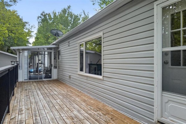 Wooden deck with black railing overlooking a wooded area and the side of a mobile home. - 19 Nature Drive, Ste Anne Rm