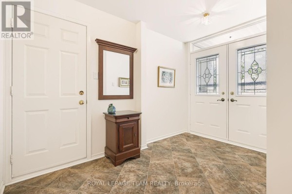 Interior entryway with beige tile flooring, white doors, and a wooden console table. - 19 Pine Needles Court, Ottawa