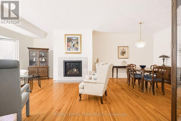 Living and dining area with hardwood floors, fireplace, and furniture. - 19 Pine Needles Court, Ottawa