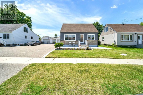 Front exterior view of a bungalow with a dark grey facade, stone accents, and a green lawn. - 19 Pleasantview Avenue, Brampton