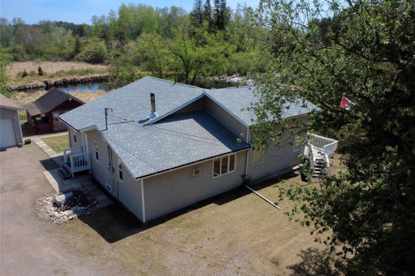 Aerial view of a beige house with a deck and stairs, next to a small shed. - 19 Rink Road, Rennie