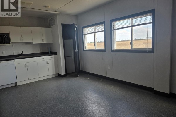 Interior room with white cabinetry, a sink, refrigerator, and two windows with blinds overlooking a field. - 19 Rocky Mountain Way, Orkney Rm No  244