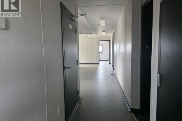 Interior hallway with white walls, black doors, grey flooring, and fluorescent lighting. - 19 Rocky Mountain Way, Orkney Rm No  244