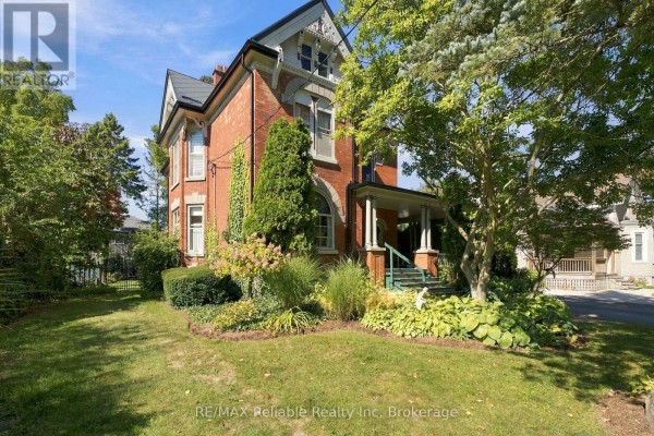 Side exterior view of a brick house with a covered porch and landscaping. - 19 Sparling Street, Huron East