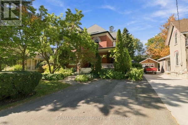Front exterior view of a brick house with a covered porch, driveway and garage. - 19 Sparling Street, Huron East