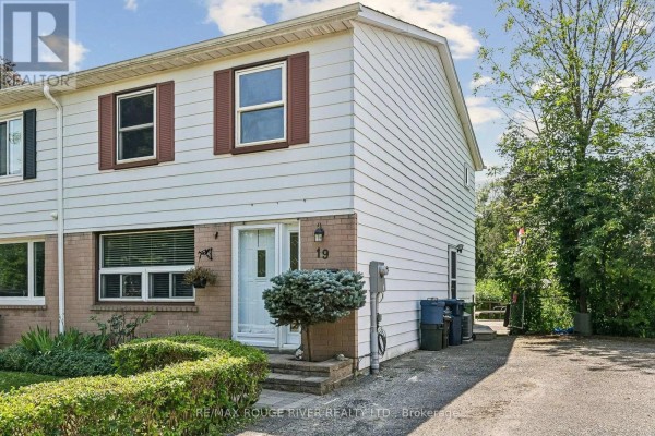 Side exterior of townhouse at 19 Tinbury Place showing white siding and side yard. - 19 Tinbury Place, Toronto