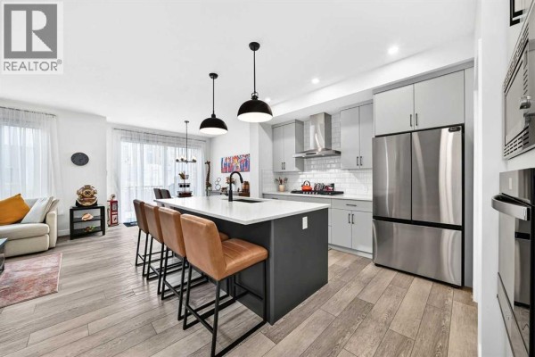 Open concept living room and kitchen with grey cabinets, white countertops, and island. - 19 Versant View Sw, Calgary