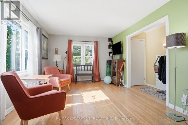 Living room with two orange chairs, a wooden chest, and an archway to another room. - 19 Victoria Street, Brant