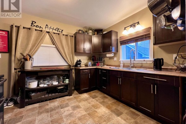 Kitchen with dark brown cabinets, brown countertops, and beige tiled floor. A stainless steel sink is visible. - 19 Wolf Street, Tillsonburg