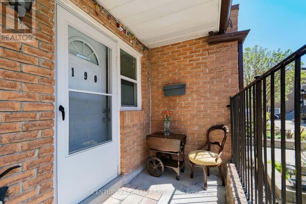 Close-up of a townhouse entrance with a white door, numbered 190, brick facade, and seating. - 190 - 50 Scarborough Golf Club Road, Toronto