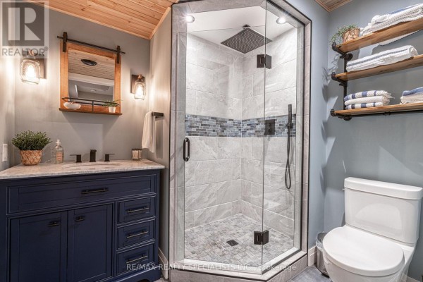 Glass-enclosed shower, navy vanity, and pipe shelves - 190 Courtland Street Blue Mountains