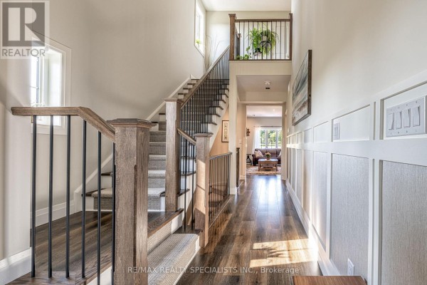 Interior hallway with hardwood floors, a staircase with wood and black metal railings, and wainscoting. - 190 Courtland Street, Blue Mountains