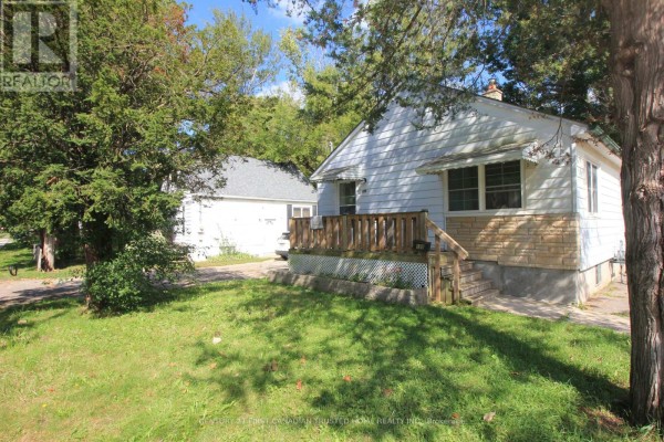Side view of the white bungalow showing the wooden porch and mature trees. - 190 Helena Avenue, London South