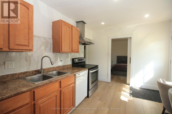 Kitchen with wood cabinets, stainless steel appliances, double sink, and tiled backsplash. - 190 Helena Avenue, London South