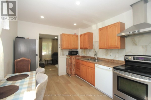 Kitchen with wood cabinets, sink, stove, dishwasher, and view into dining and living areas. - 190 Helena Avenue, London South