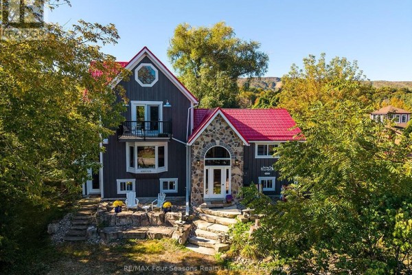 Front view of a grey house with a red roof, stone entrance, stone steps, and two white Adirondack chairs on a patio. - 190 Lakeshore Road E, Blue Mountains
