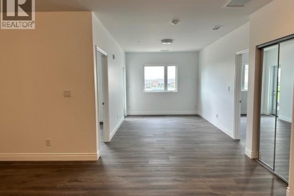Living area with dark wood laminate flooring, white walls, and mirrored closet doors. - 1900 Concession Rd 6 Unit# 205, Lasalle