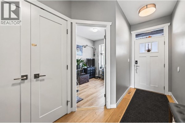 Entrance hallway with white doors, light wood floors, and grey walls. - 1900 Ord Road Unit# 21, Kamloops