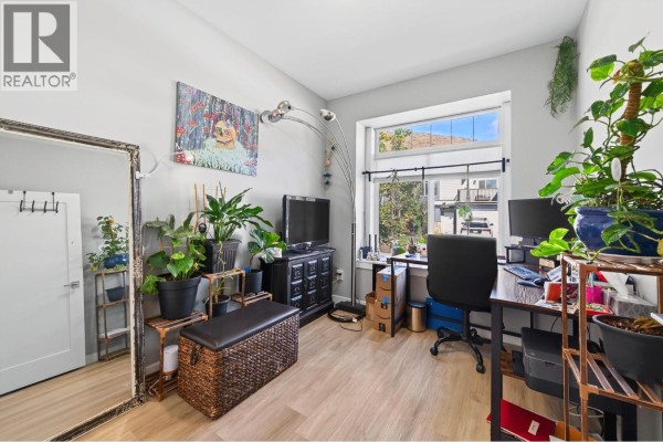 A bright home office with a large window, light wood floors, and plants. - 1900 Ord Road Unit# 21, Kamloops